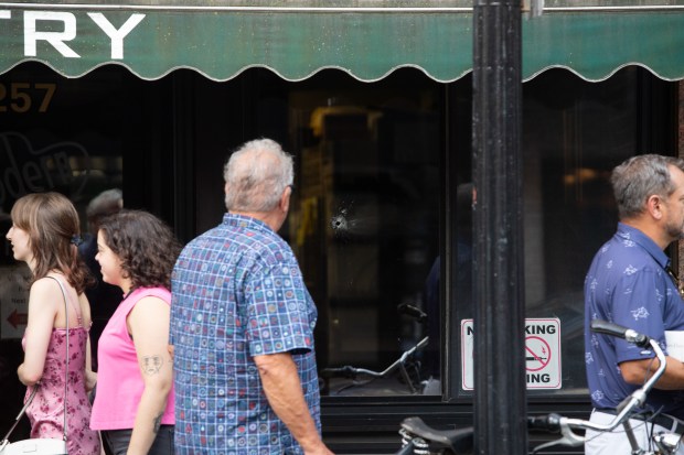 A man looks at a bullet hole in the window of Modern Pastry. A 54-year-old Boston man is accused of firing a weapon in the North End Wednesday night. (Chris Van Buskirk/Boston Herald)