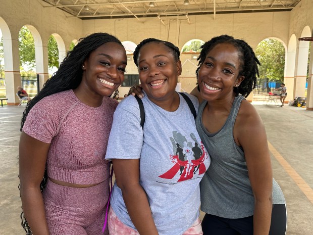 Three women pose and smile.